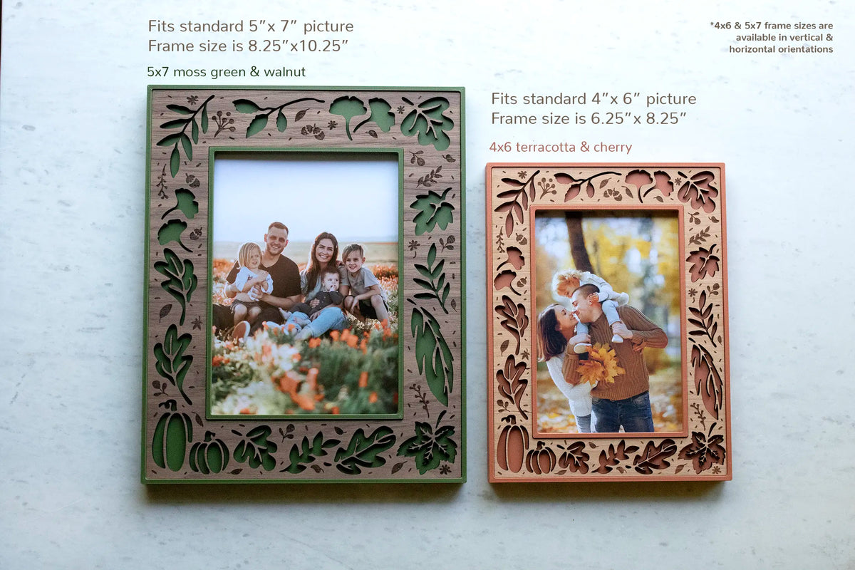 Size comparison of two fall leaf picture frames — a 5×7 in moss green with a walnut inlay (8.25×10.25″ outer) and a 4×6 in terracotta with a cherry inlay (6.25×8.25″ outer), both available in vertical and horizontal. Laser-cut with autumn leaves, pumpkins, and acorns, each holding a fall family portrait — handmade fall and Thanksgiving decor.