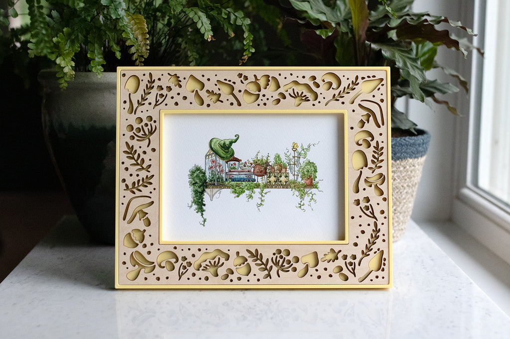 Large yellow 5x7 mushroom picture frame with delicate laser cut mushroom design. The handcrafted frame is yellow with a light maple wood inlay. 5x7 picture frame is displaying a picture of a garden witch's shelf.
