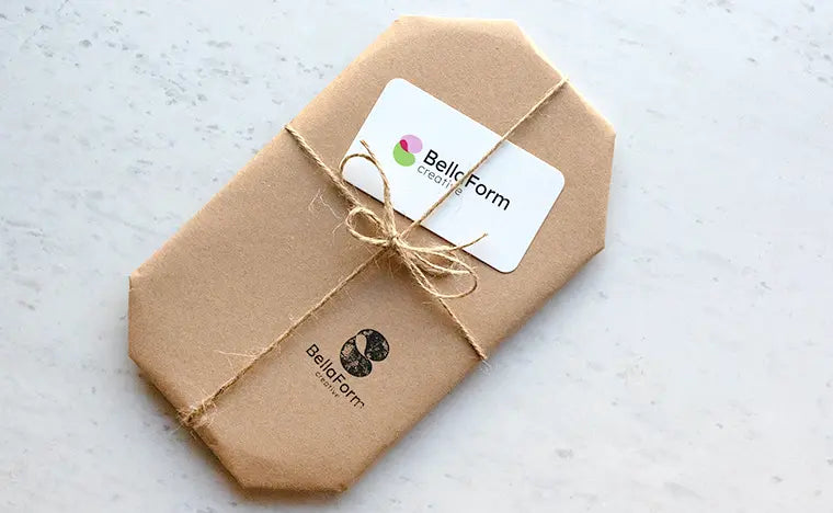 A set of bookends from BellaForm Creative gift wrapped in brown kraft paper and tied with a piece of natural hemp twine. Includes a hand stamp in black ink and a business card.