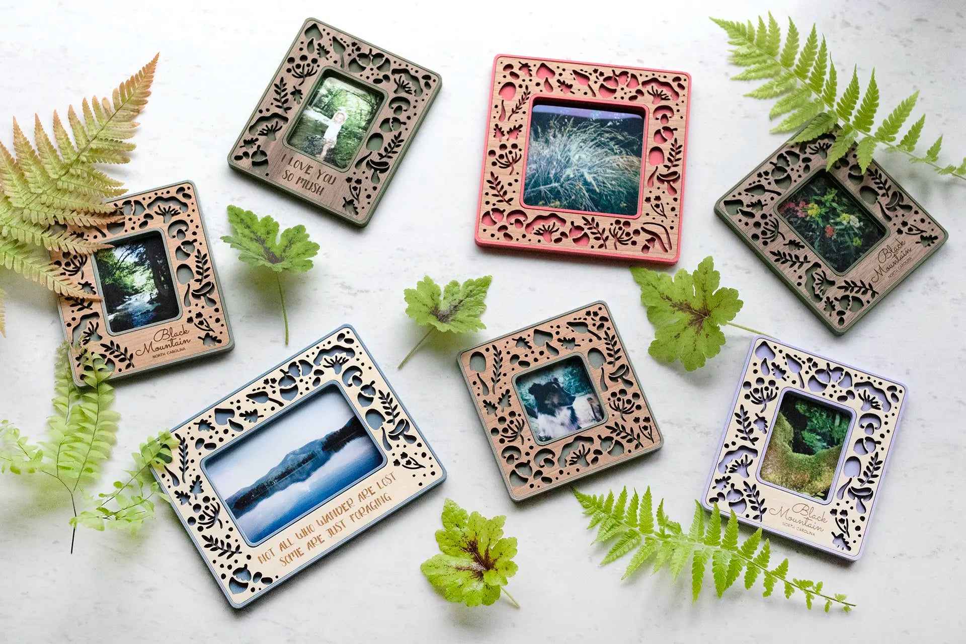 Custom laser cut magnetic frames with mushroom decor. Pictured are instax mini frames, instax wide, polaroid Go, and standard polaroid frames. The frames are surrounded by natural ferns and greenery.