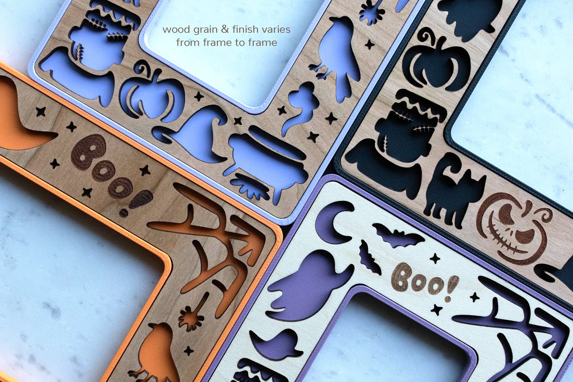 Close-up view of purple, orange, and black mini Halloween picture frames with magnets. Frames feature black cats, Frankenstein, pumpkins, ghosts, and a starry night sky with moon and stars.