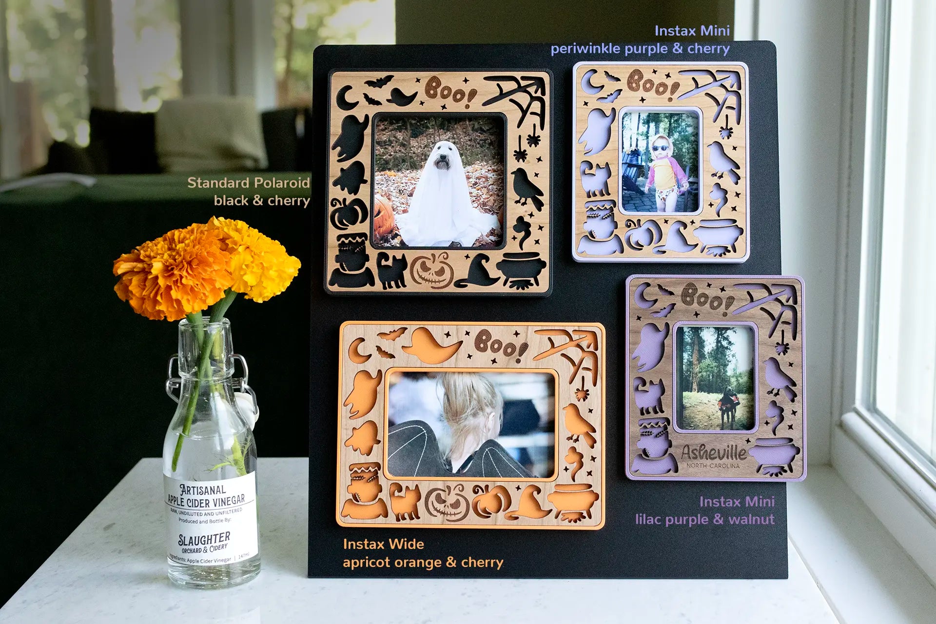 Laser cut Halloween picture frame with magnets for the fridge. Frames are displayed on a magnetic surface and available in purple, orange, and black. Frames feature cut-outs of ghosts, pumpkins, Frankenstein, black cats, and more. Sizes include Instax Mini, Instax Wide, and Polaroid frames.