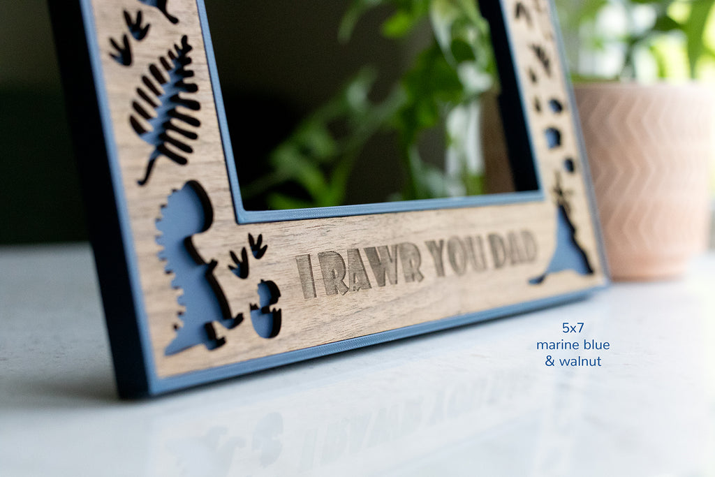Custom engraved dinosaur frame with message "I RAWR YOU DAD" at the bottom of the frame. Laser cut walnut inlay with blue plastic 3D printed housing.