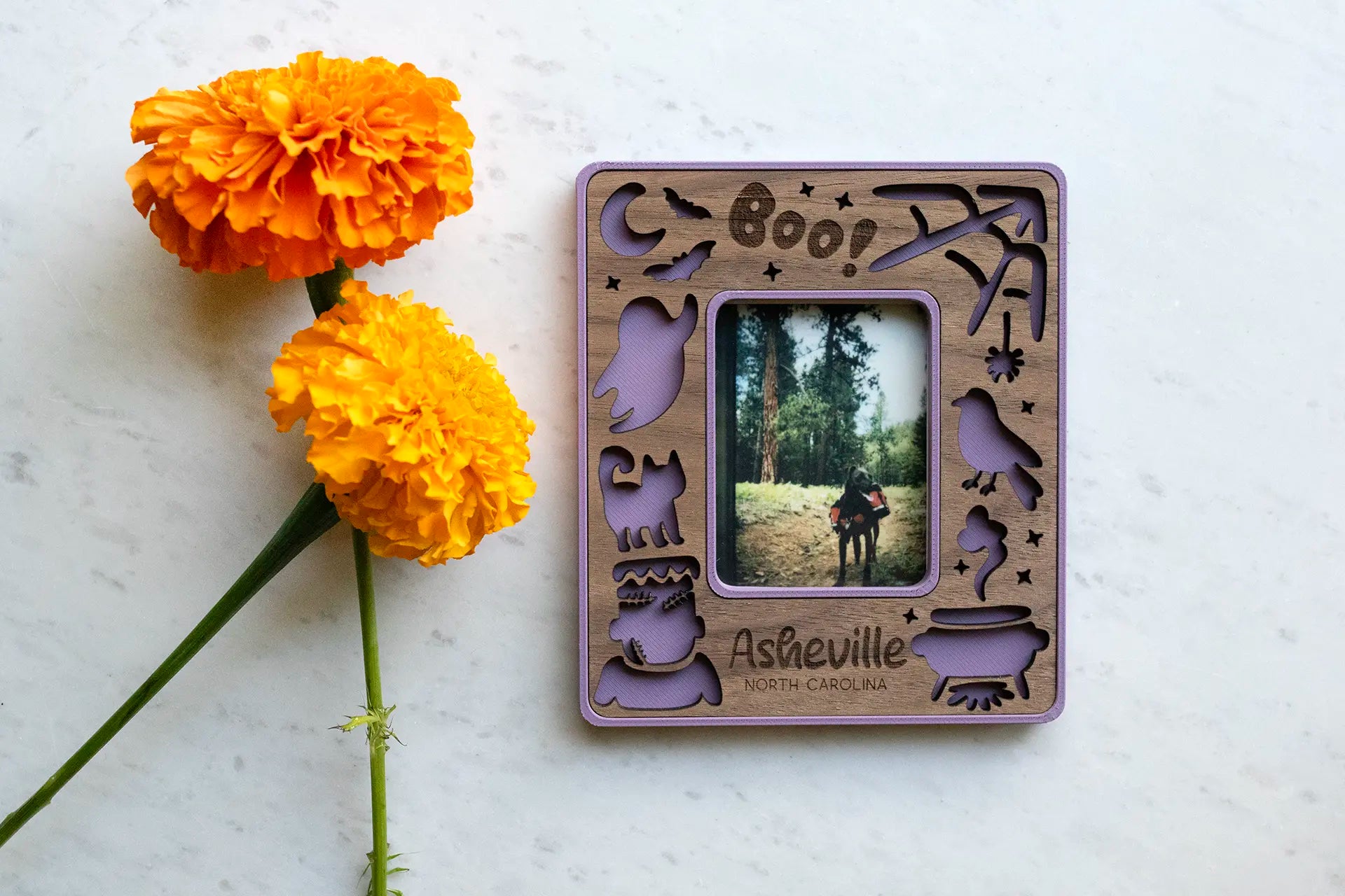 Purple Instax mini magnetic frame with Halloween design, including laser-cut ghosts, pumpkins, cute Frankenstein, witch's cauldron, broomstick, and witch's hat. The frame displays an Instax Mini photo of a dog with a backpack.