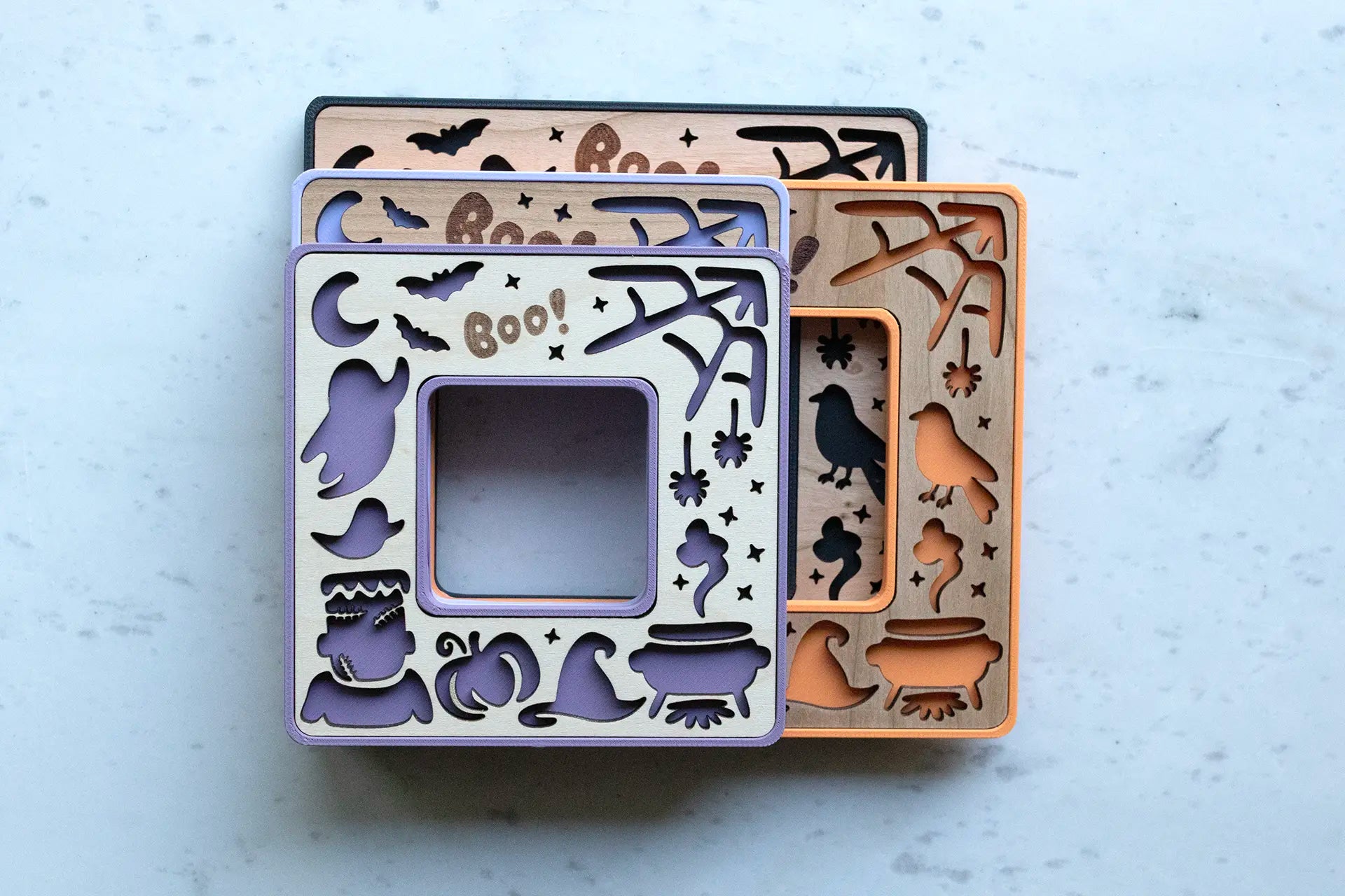 Mini Halloween keepsake picture frames with laser engraved Boo! and laser cut pumpkins, ghosts, and little Frankenstein. Frames come in purple, orange, and black.