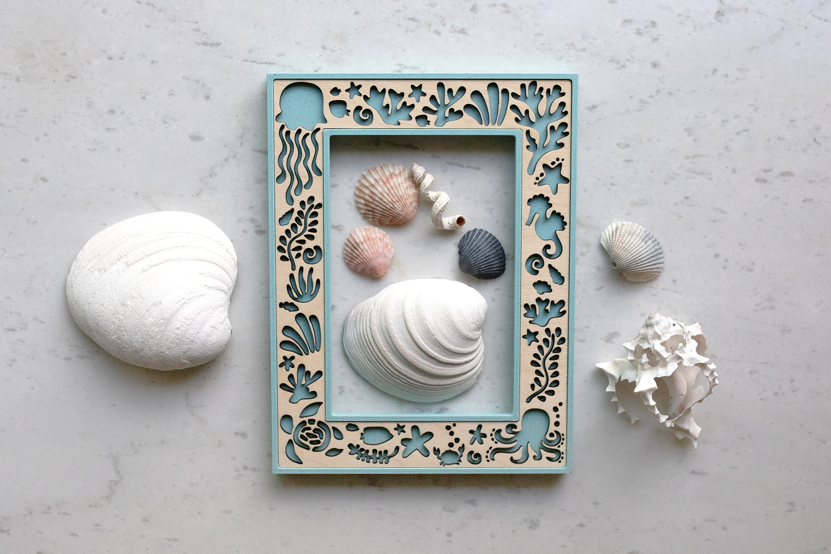 Light blue laser cut picture frame with ocean creatures, including starfish, jellyfish, a sea turtle, octopus, and seaweed. Frame has a custom laser cut maple wooden inlay.