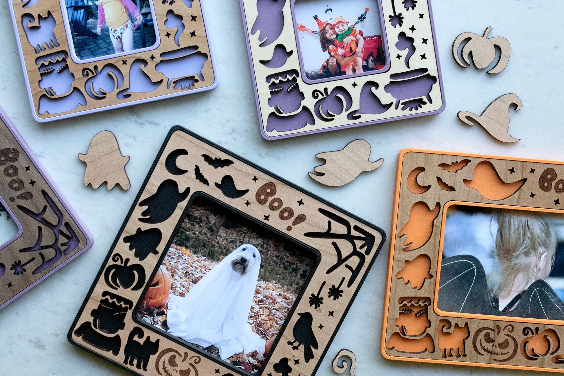 Assortment of purple, orange, and black Halloween instant photo picture frames with magnets. Frames feature cute Halloween designs, including laser cut ghosts, pumpkins, and black cats. There are laser cut shapes surrounding the picture frames.