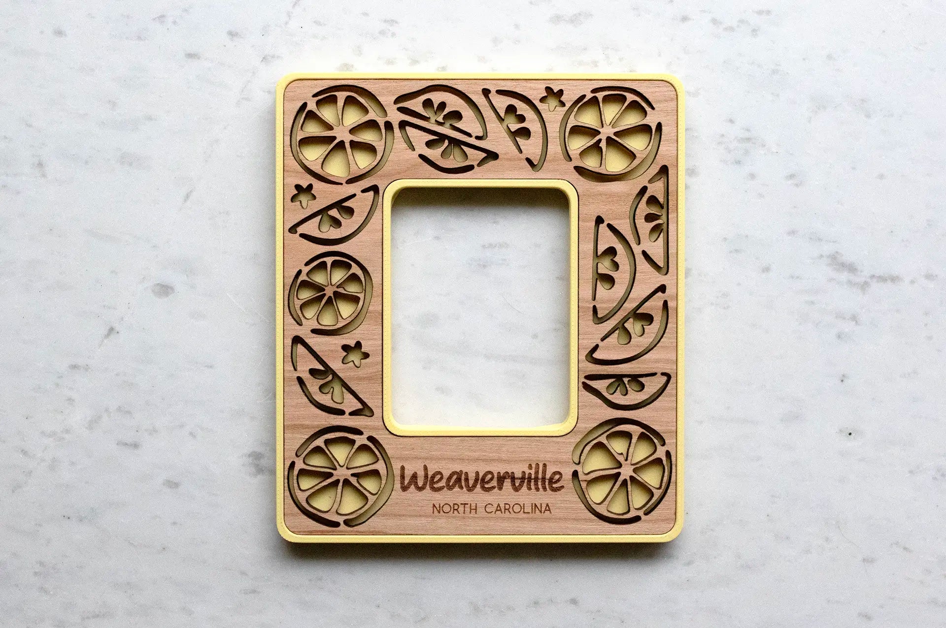 Personalized lemon picture frame for Instax Mini photos. Frame is yellow with a cherry wood inlay and the words "Weaverville North Carolina" engraved.