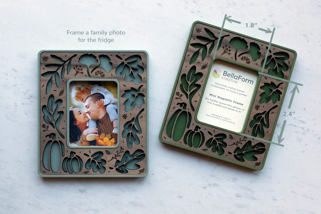 Two fall leaves magnetic frames in sage green and walnut and moss green and walnut, one holding a family photo and one showing a 1.8" x 2.4" photo window that fits Fujifilm Instax Mini photos and wallet size photos.