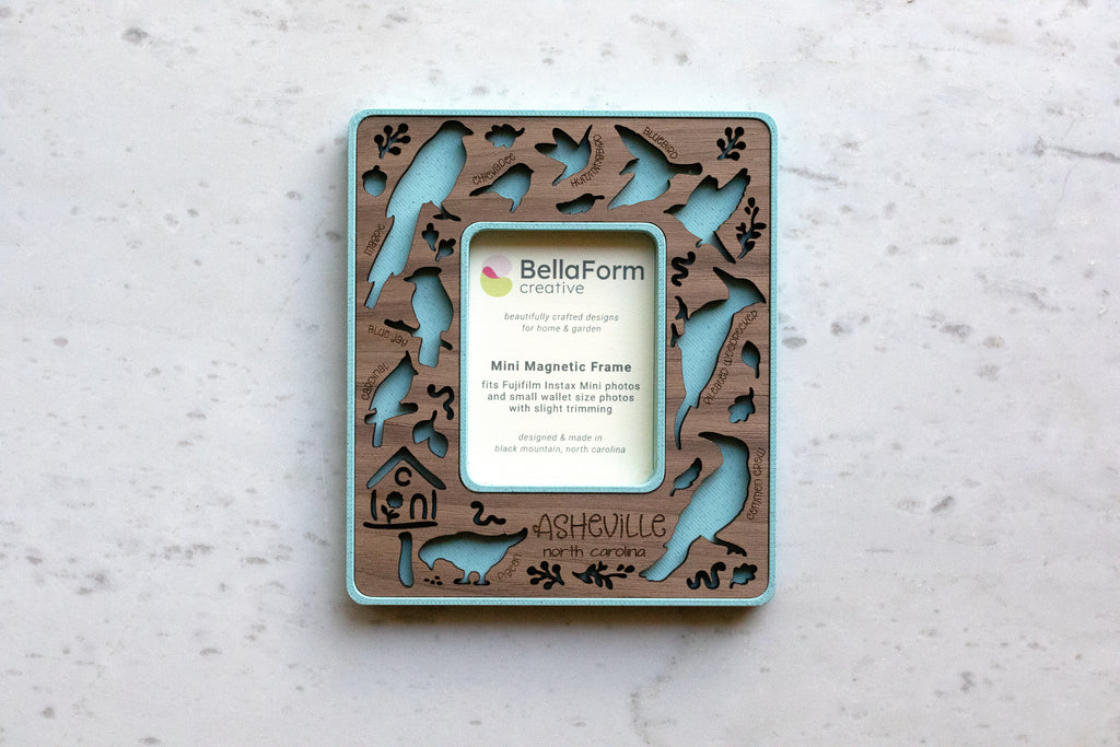 Magnetic frame for the refrigerator that features birds of north carolina, including: hummingbird, crow, pigeon, blue jay, chickadee, bluebird, pileated woodpecker, and cardinal. This frame is a mini magnetic frame to fit instax mini photos, making it a great small gift for bird lover friends.
