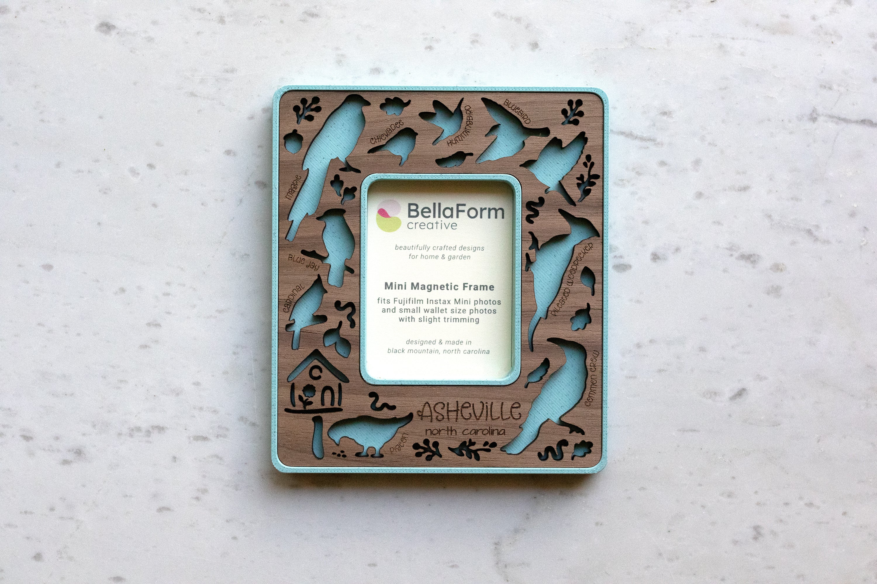 Magnetic frame for the refrigerator that features birds of north carolina, including: hummingbird, crow, pigeon, blue jay, chickadee, bluebird, pileated woodpecker, and cardinal. This frame is a mini magnetic frame to fit instax mini photos, making it a great small gift for bird lover friends.