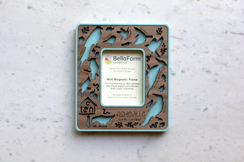Magnetic frame for the refrigerator that features birds of north carolina, including: hummingbird, crow, pigeon, blue jay, chickadee, bluebird, pileated woodpecker, and cardinal. This frame is a mini magnetic frame to fit instax mini photos, making it a great small gift for bird lover friends.