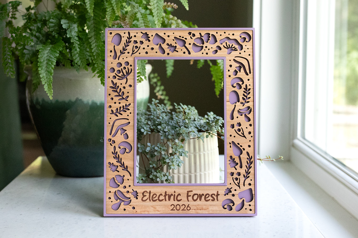 Custom purple mushroom picture frame with laser engraved text that reads "Electric Forest 2026" on the bottom of the frame. This 5x7 frame is made with a laser cut cherry wood inlay and makes a perfect festival gift or festival memorabilia.