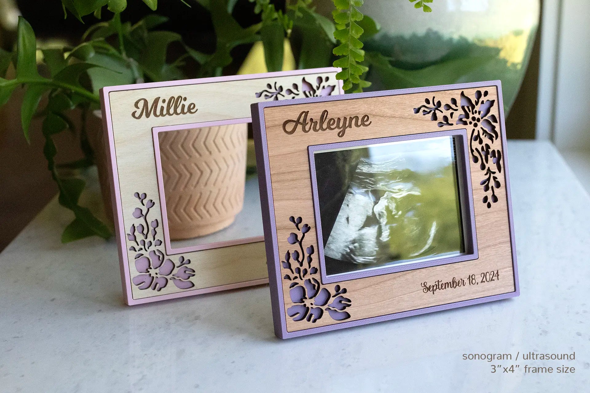 Two ultrasound frames in pink with a floral maple design and purple with a floral cherry design. The front floral frame displays an ultrasound photo. This frame style makes a great gift for new mom.