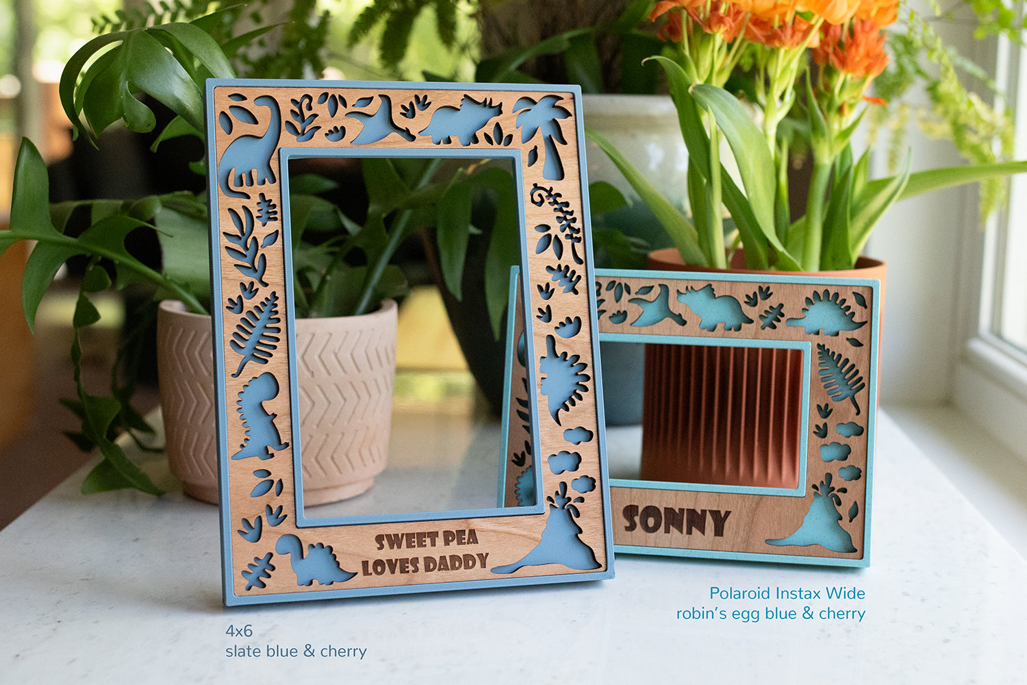 Two cute picture frames featuring a dinosaur theme, making it a great gift for a dinosaur baby shower or boy room decor. The frames have 3D printed borders that are shades of blue with a laser cut cherry wood inlay.