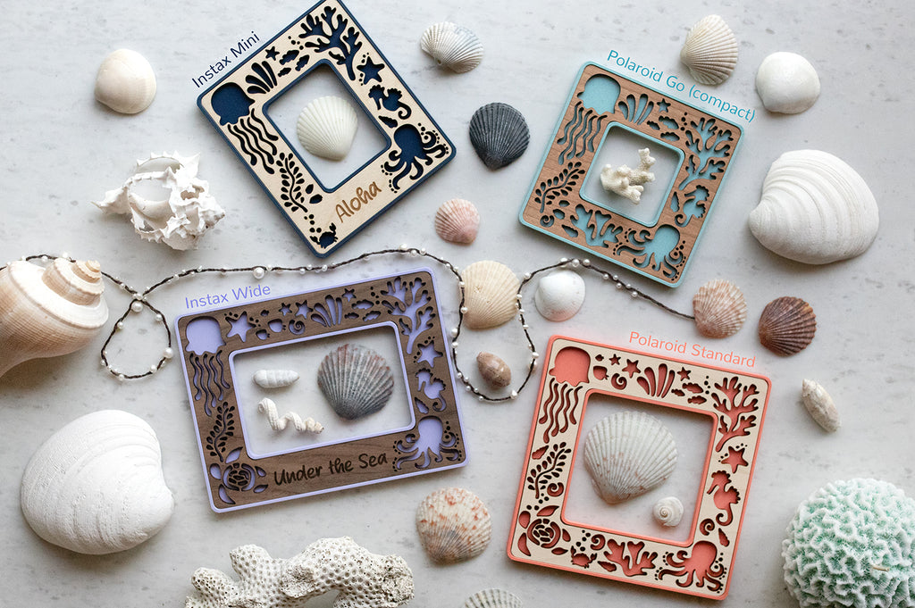 Sea creatures mini frames in four sizes: Instax wide frame, Instax mini frame, Polaroid Go frame, and standard Polaroid frame. The frames are navy, light blue, purple, and coral, and they are surrounded by seashells and pearls.