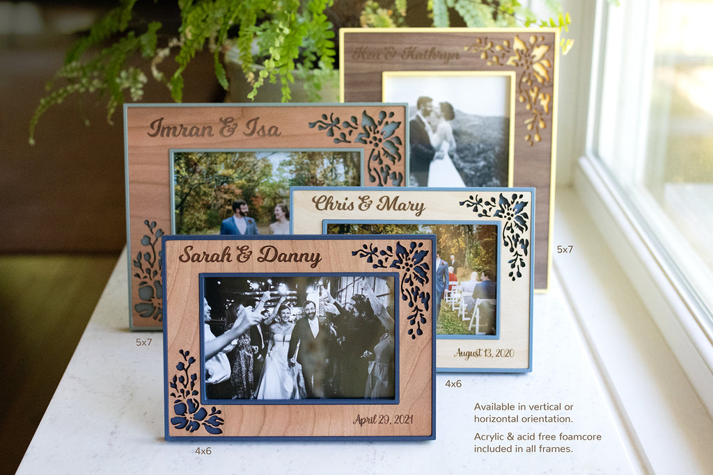An assortment of wedding picture frames shown in 5x7 inch sizes and 4x6 inch sizes. The frames are pale yellow, sage green, slate blue, and navy blue with various colored wooden borders. The image reads "Available in vertical or horizontal orientation. Acrylic and acid free foamcore included in all frames."