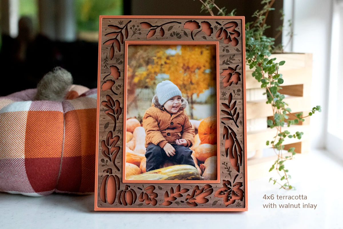 Fall Picture Frame in terracotta with walnut wood inlay featuring autumn leaves and pumpkins, holding a 4x6 photo of a smiling toddler sitting on pumpkins