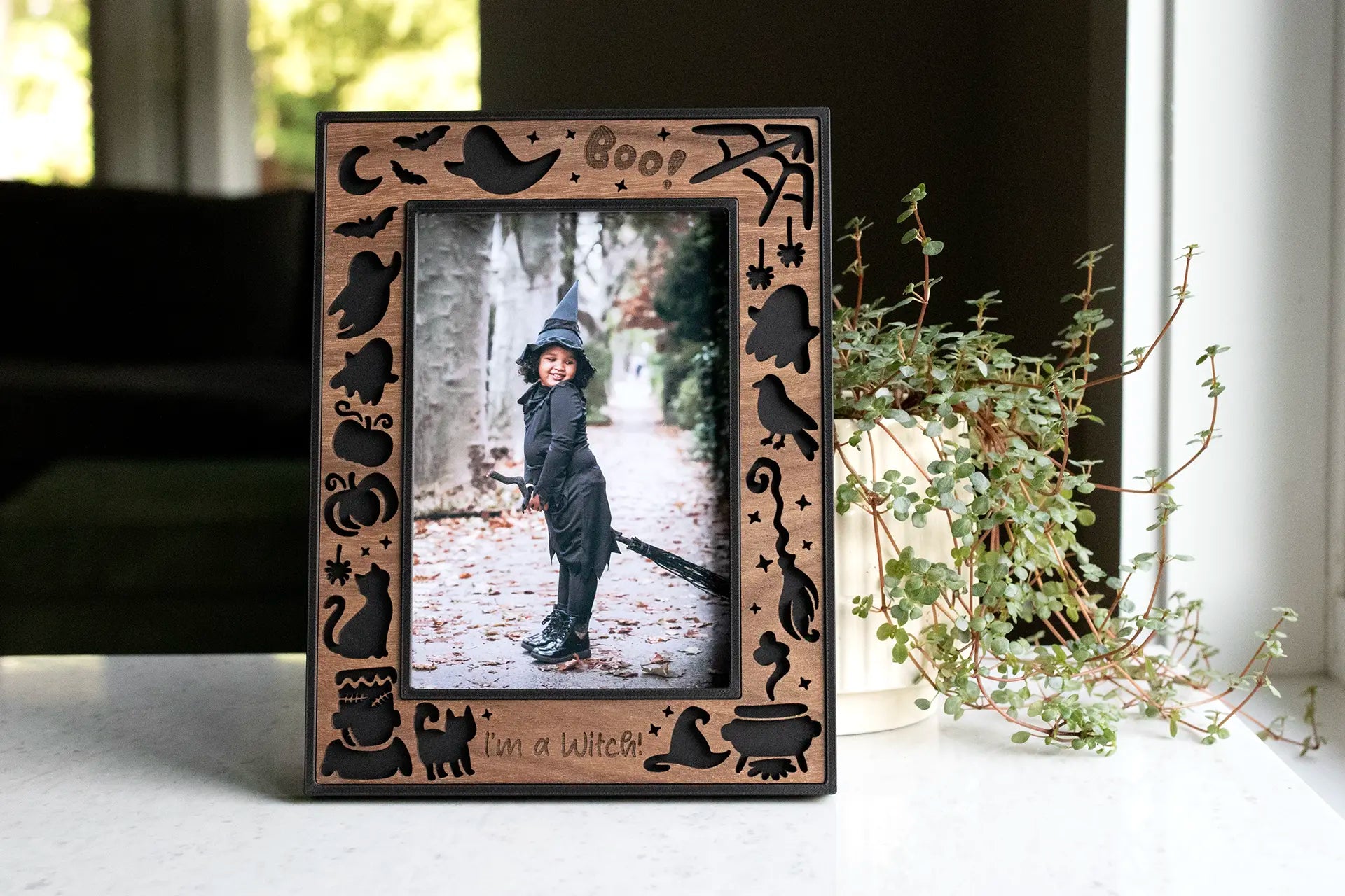 Halloween picture frame with ghosts, witch's broom, hat and cauldron, pumpkins, spiders, and bats. The frame housing is black with a laser-cut walnut inlay. Makes a beautiful seasonal Halloween keepsake to keep year after year. 