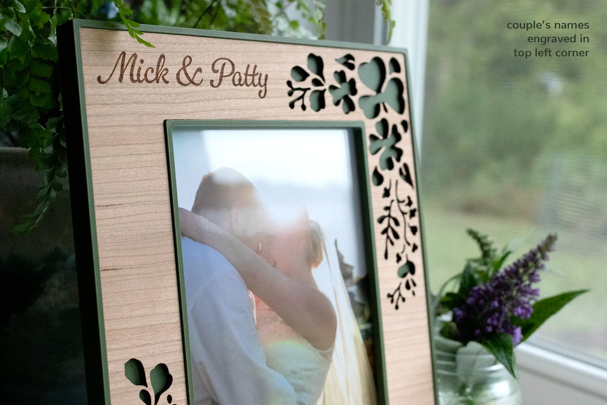 A personalized laser-cut wedding picture frame with shamrocks and trailing clover to celebrate an Irish wedding. The frame displays a photograph of a couple embracing at their wedding.