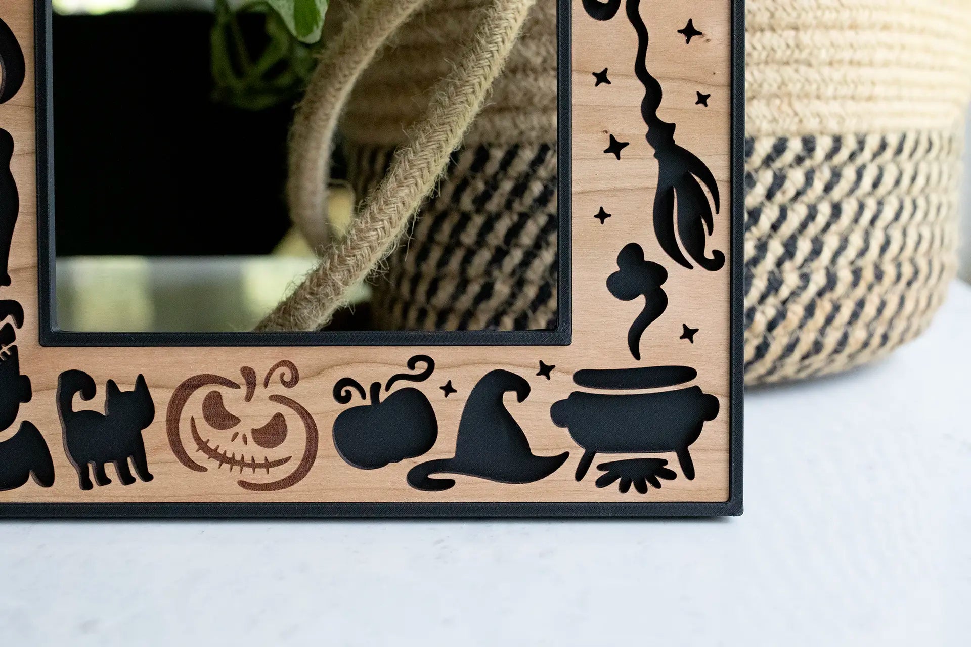Close-up, detail view of a personalized laser Halloween photo frame with laser cut witch's hat, witch's broomstick, cauldron, pumpkins, and black cats in the bottom-right corner.