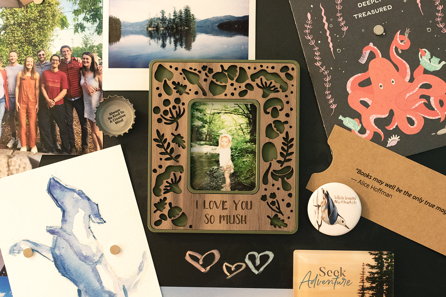 A magnetic mushroom Polaroid photo frame for Instax Mini hanging on a black, magnetic chalkboard. The frame has a walnut inlay and a green border and includes the customized message: "I love you so mush". The frame is surrounded by postcards and photographs. This mini picture frame has a whimsical design.