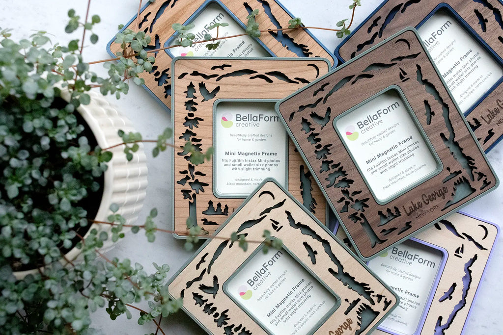 Laser-cut Lake George magnetic frames with wooden inlays. Frames feature the silhouette of Lake George New York, Adirondack mountains in the distance, loons on the lake, osprey flying in the sky, evergreens on islands in the lake, the Lac Du Saint Sacrement tour boat, and a pair of kayakers.