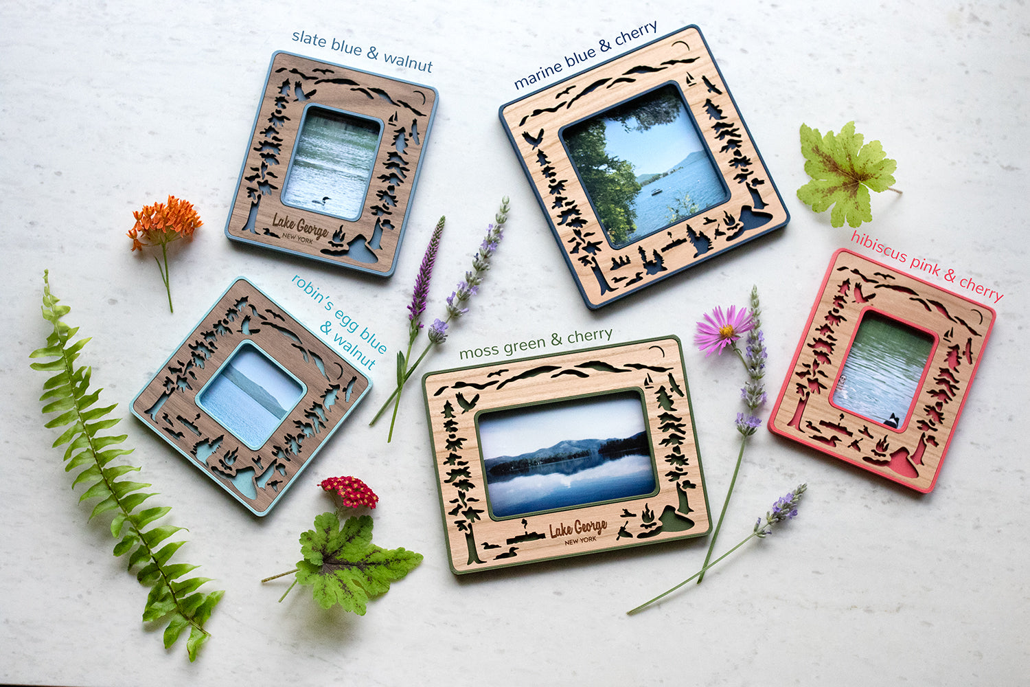 An assortment of five mini magnetic frames, including Instax Mini, Instax Wide, Polaroid Standard, and Polaroid Go sizes. Frames have an assortment of different colors and wood types. Featuring unique laser cut scenes from beautiful Lake George New York.