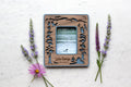 Lake George New York magnetic polaroid frame in Instax Mini frame size. The frame features laser cut Adirondack mountain, evergreen trees, loons, osprey, and kayakers on Lake George. The mini frame is lying next to wildflowers and displays a photo of a loon swimming on the lake.