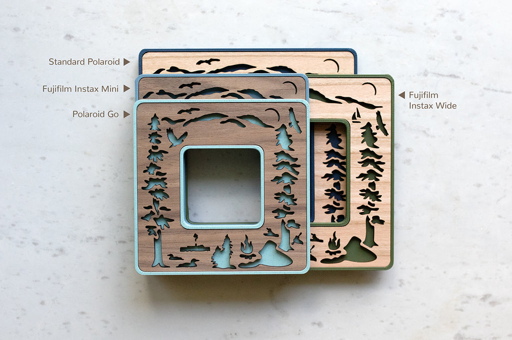 A stack of four mini polaroid frames including sizes for: Instax mini, Instax wide, Polaroid Go, and Polaroid Standard. The laser cut designs feature elements from Lake George NY - including evergreen trees, adirondack mountains, the Lac Du Saint Sacrament boat, loons, kayakers, and a campfire.