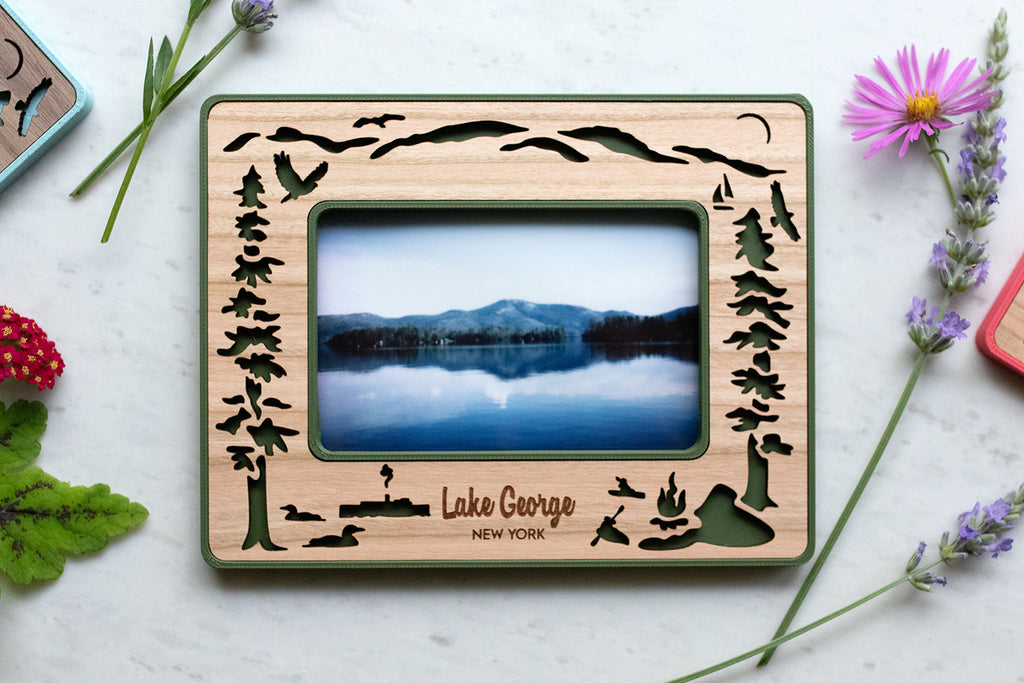 Instax Wide frame for Lake George lovers. Frame design includes adirondack mountains, evergreen trees, and various wild bird species that are commonly found at the lake in upstate New York. A design for lake goers and lake houses.