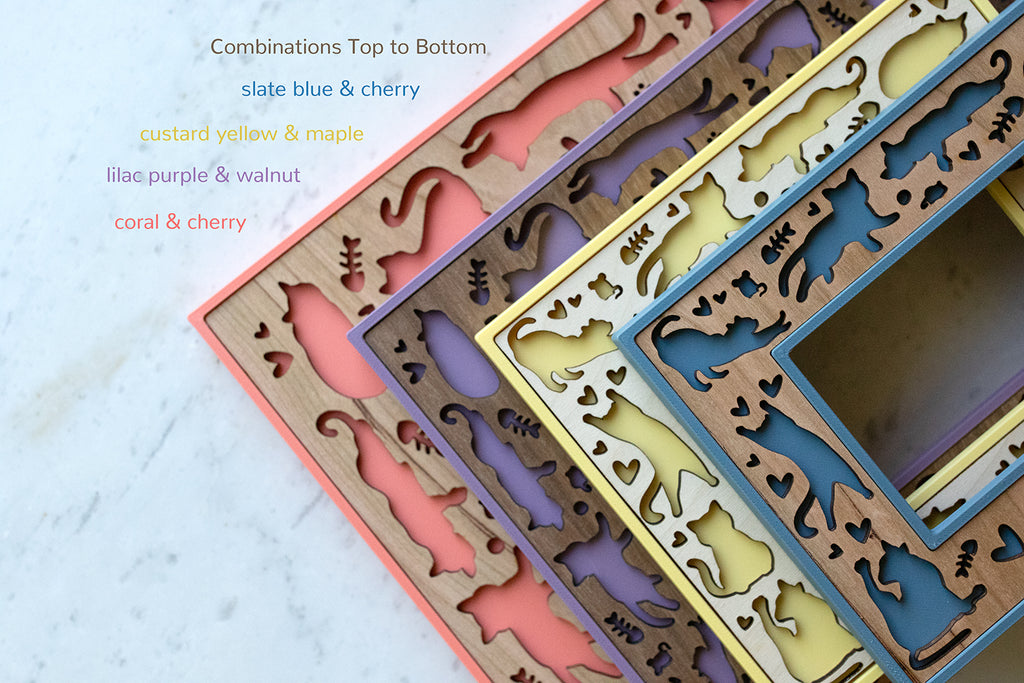 A close-up, detail view of four cat picture frames with cute, laser cut cat designs. The frames are stacked on top of each other. The frames come in a variety of colors and wood types, including maple, walnut, and cherry. The frames have playful, whimsical designs, and the laser cut inlays can be personalized with cat names and brief messages.