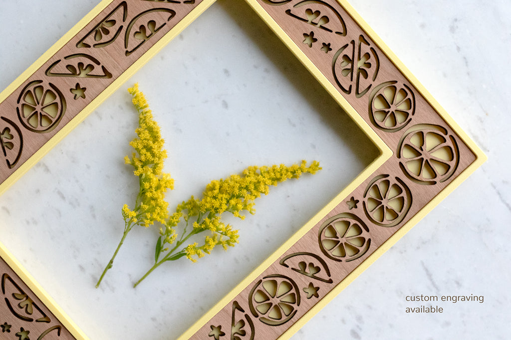 A close-up, detail view of a pretty laser cut lemon frame. There is a note on the image that reads "custom engraving available" to make a special gift for the fruit lovers in your life.
