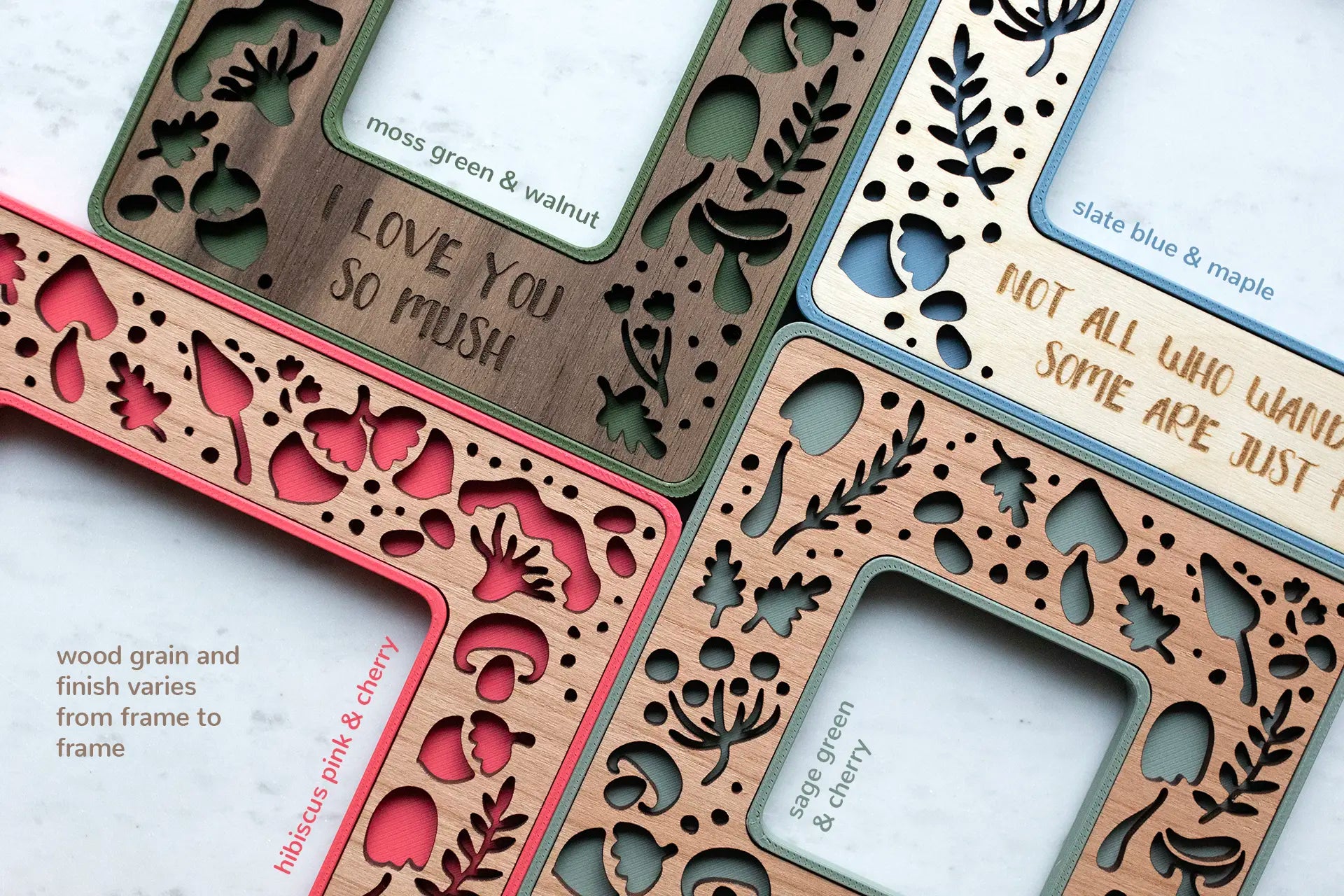 A close-up, detail view of four mini frames with unique mushroom designs, in various colors, including pink, moss green, sage green, and slate blue. The bottom left corner of the image reads "wood grain and finish varies from frame to frame". Personalized mushroom gifts.