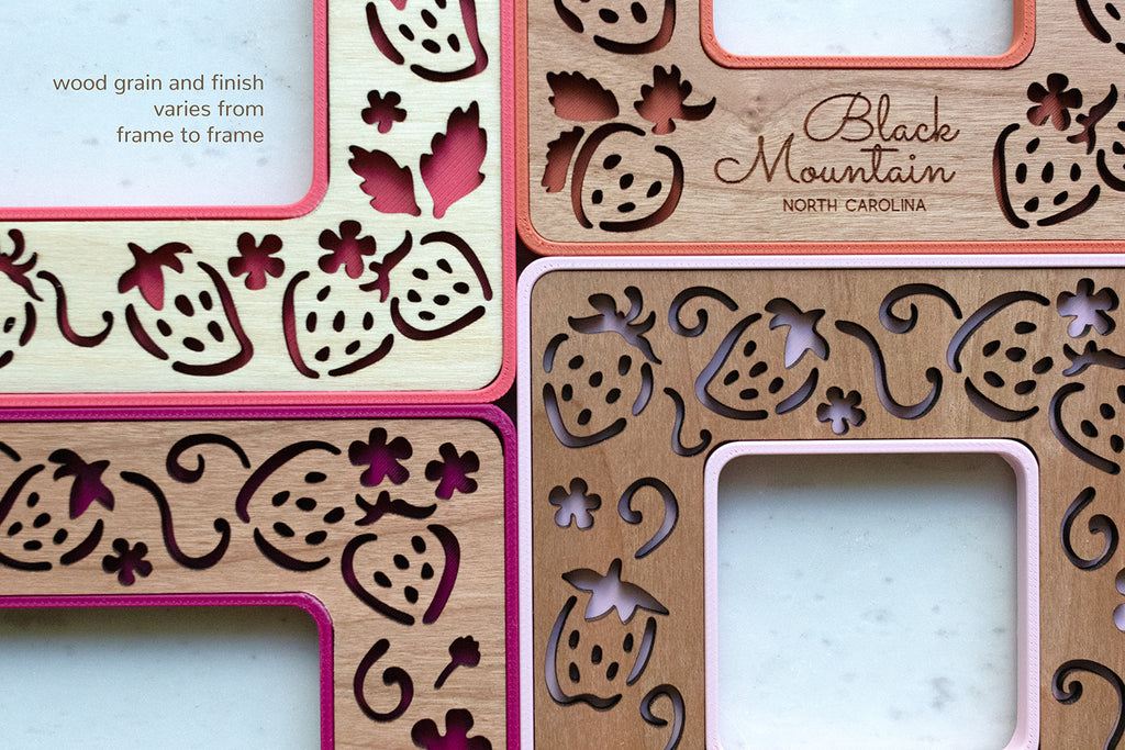 A close-up, detail view of four mini strawberry frames in various shades of pink and red with the message "wood grain and finish varies from frame to frame" in the top leftmost corner.