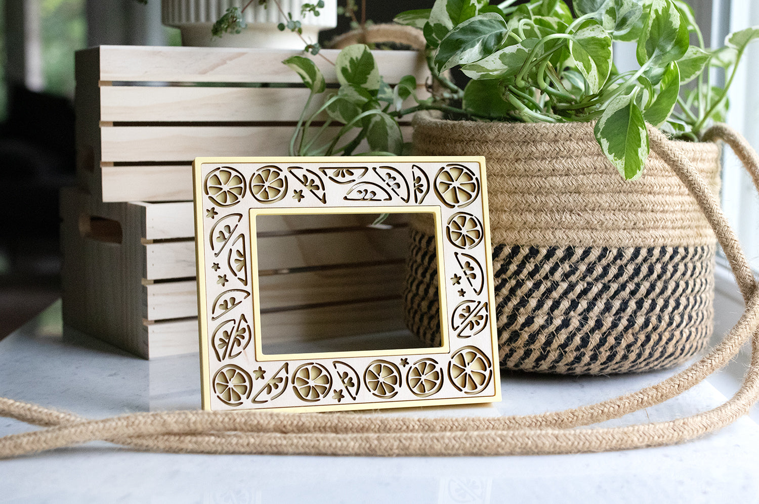 Lemon picture frame that fits Fujifilm Instax wide film size. The frame is a light yellow color and has natural greenery and wooden crates in the background.