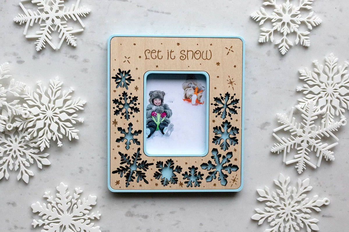 Personalized snowflake magnetic picture frame for winter home decor. This Instax Mini frame is laser-cut with delicate snowflakes and engraved with falling snow. Designed to hold your favorite Instax Mini photo or a wallet photo trimmed to size.