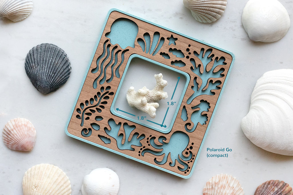 Blue Polaroid Go beach frame with cute laser cut sea creatures. The frame opening is 1.8" x 1.8" and is surrounded by seashells. The frame has a cherry wood inlay.