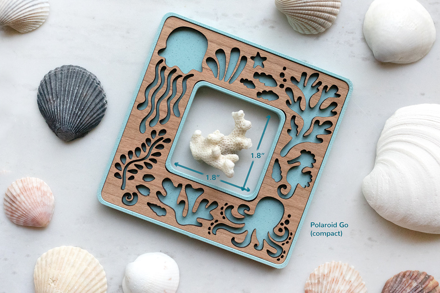 Blue Polaroid Go beach frame with cute laser cut sea creatures. The frame opening is 1.8" x 1.8" and is surrounded by seashells. The frame has a cherry wood inlay.