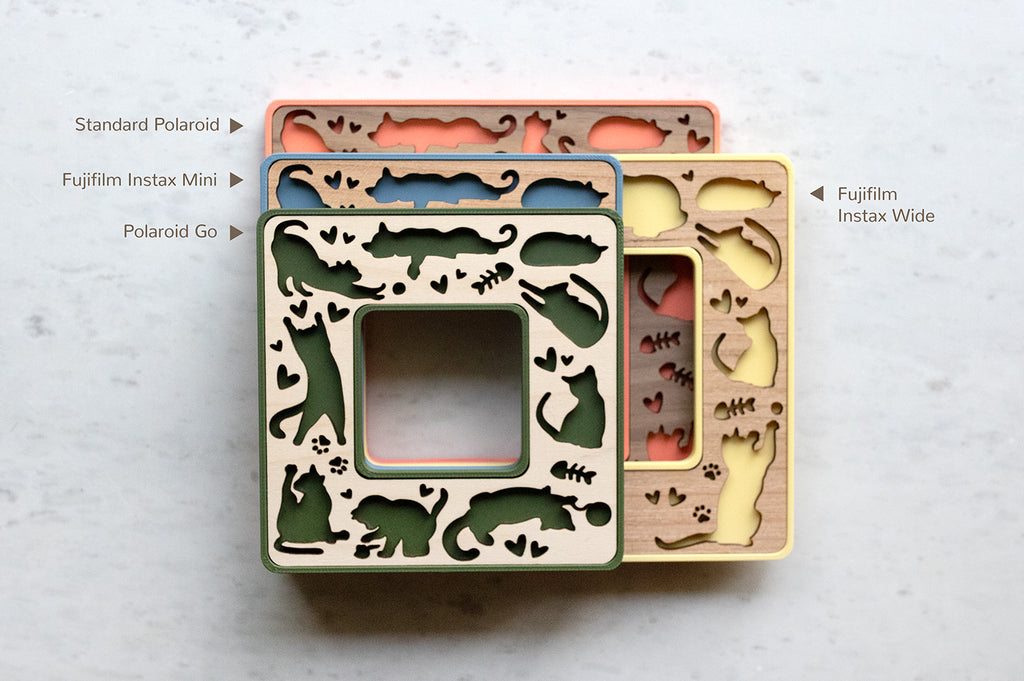 Four whimsical laser cut magnetic cat frames. The mini cat frames are shown in blue, coral pink, moss green, and yellow. The wooden inlays are available in maple, walnut, and cherry wood. Frame sizes include Instax Mini, Instax Wide, Polaroid Go, and Polaroid Standard/iType/SX-70/600.