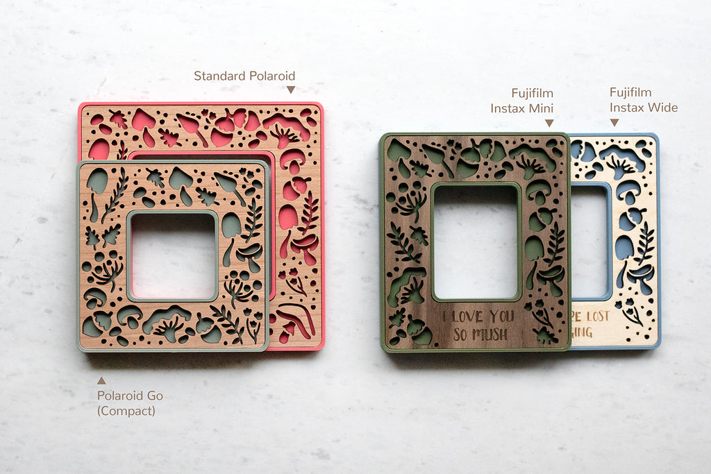 Four mini polaroid frames and Instax mini and Instax wide frames. The frames feature laser cut mushrooms, acorns, and other woodland designs. On the left, the compact Polaroid Go size is stacked on top of the larger Standard Polaroid size. On the right, the Fujifilm Instax Mini frame is stacked on top of the Instax Wide frame, showing approximate sizing.