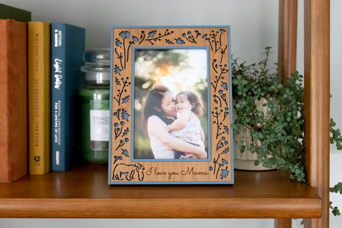 A Mama and Baby Bear picture frame with a laser-cut wood inlay of wildflowers and branches, set in a 3D-printed housing, with a mama bear and her cub in the corner. Personalize it with a laser-engraved message like “I love you Mama,” a name, or a date. It comes in 4x6, 5x7, and 6x8, plus a 3x4 size for a sonogram photo, with a choice of walnut, cherry, or maple wood. It makes a gift for a new mom, a baby shower present, a Christmas gift for mom, or a Mother’s Day keepsake.