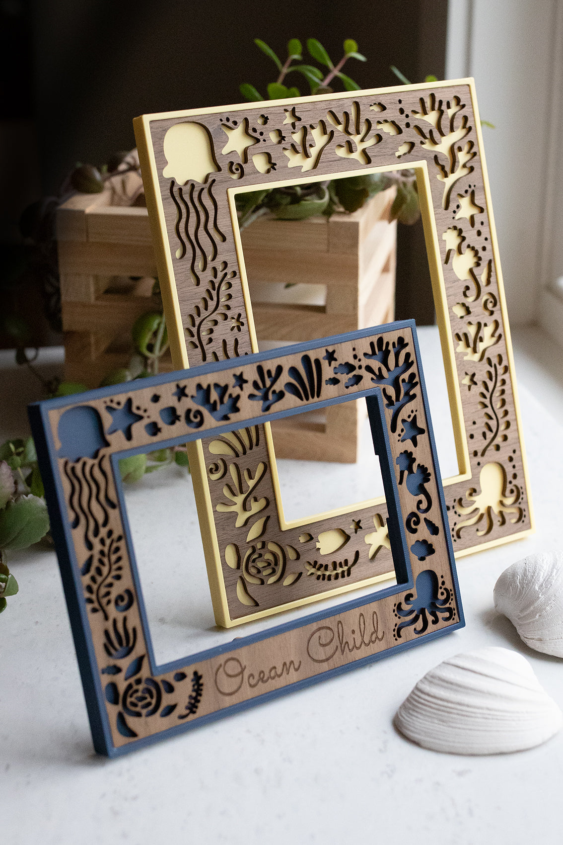 Two laser cut and laser engraved customizable picture frames. The front frame is 4x6 inch and includes a laser engraved message that reads "Ocean Child." The back frame is 5x7 and shows the ocean creature frame design without customization.