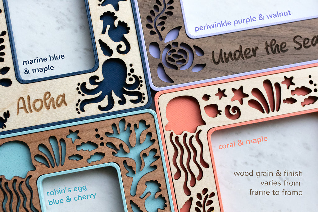 A close-up, detail view of four mini frames with sea creatures, in various colors, including coral, light blue, marine blue, and periwinkle. The bottom right corner of the image reads "wood grain and finish varies from frame to frame". Personalized frames read "Aloha" and "Under the Sea".