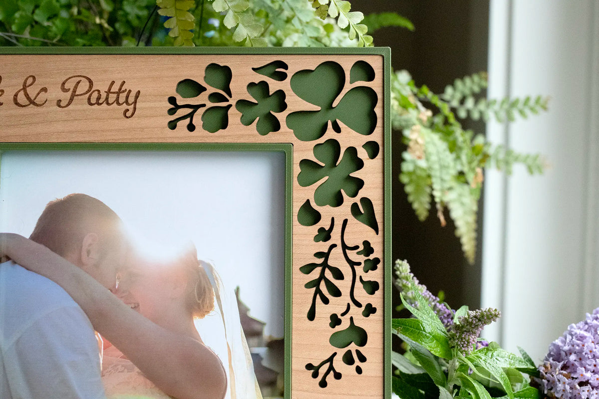 Close-up of the laser-cut clover detail on an Irish wedding shamrock picture frame in cherry wood and moss green, displaying a couple's wedding photo.