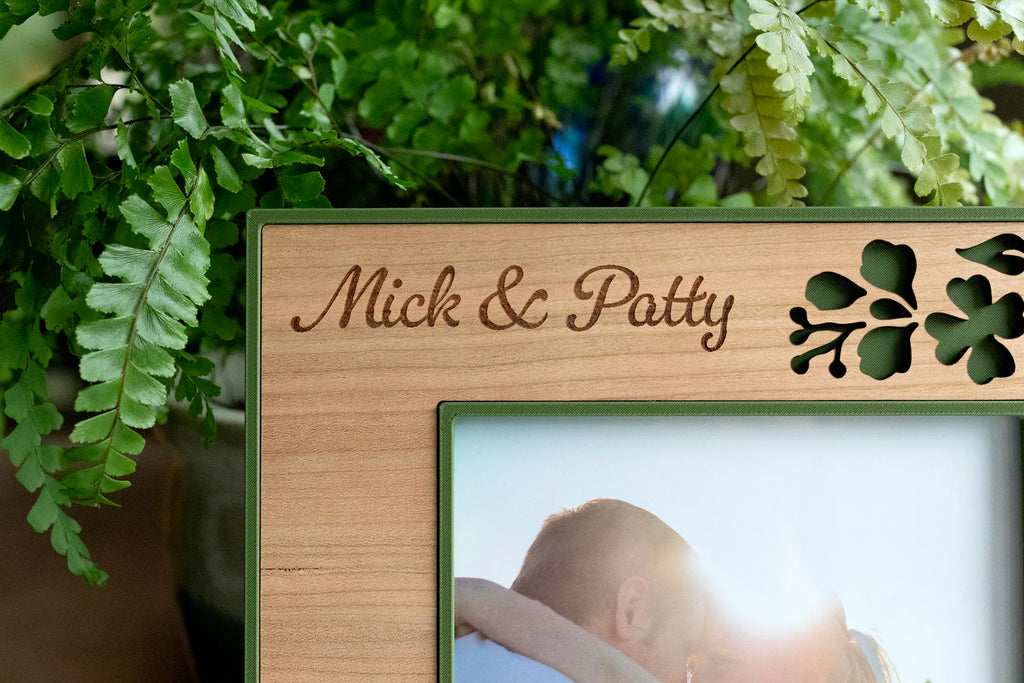 Close-up of the engraved script names "Mick & Patty" on a personalized Irish wedding shamrock picture frame in cherry wood.