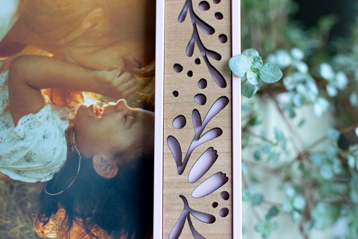 Close-up of the side of a Camellia Pink flower picture frame with laser-cut leaf cutouts and visible cherry wood grain.