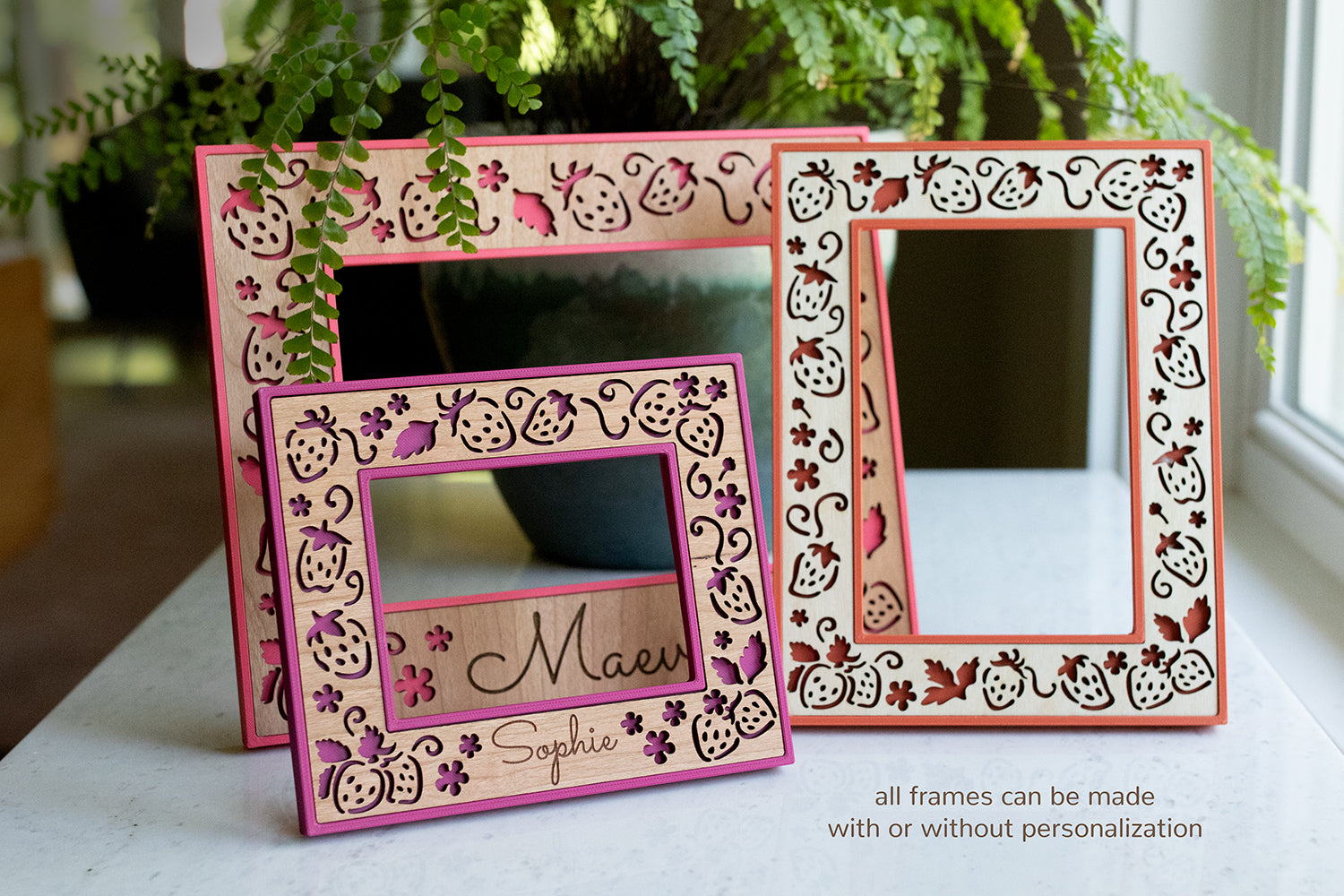 An assortment of three brightly colored laser cut frames featuring delicate strawberries and strawberry flowers on wooden inlays. Frame colors are hibiscus pink, plum pink, and poppy red. The frames are bright and playful for summer decor and girl room decor.
