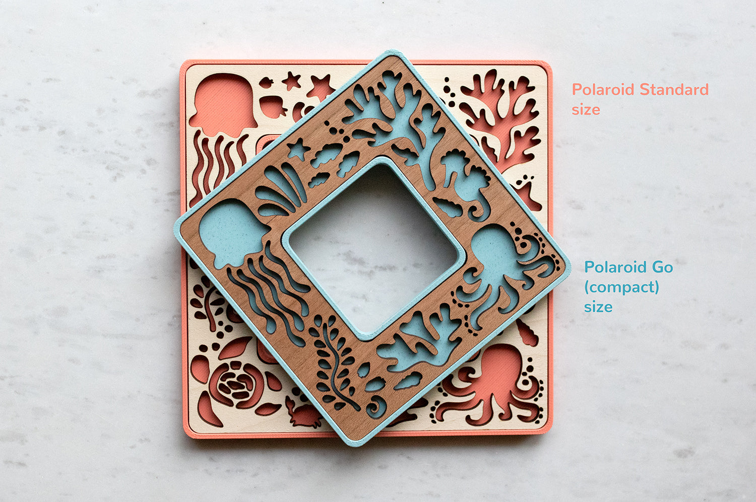 Polaroid picture frames featuring ocean animals. The frames are light blue with cherry wood and coral pink with a maple inlay. The frames hold Polaroid Go and Standard Polaroid photos.