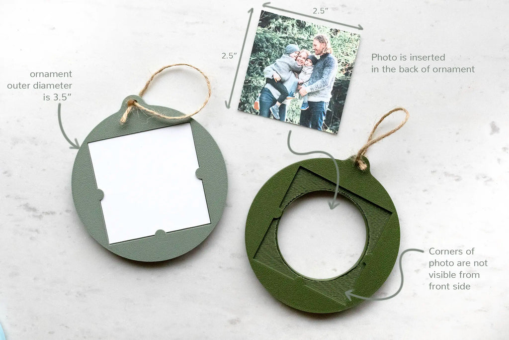 Back view of the photo ornament showing how it works: a 2.5" square photo inserts into the back of the 3.5" ornament, and the photo's corners are hidden from the front. Shown in sage green with a photo inserted and in moss green with the photo removed and lying next to it, with jute twine hangers.